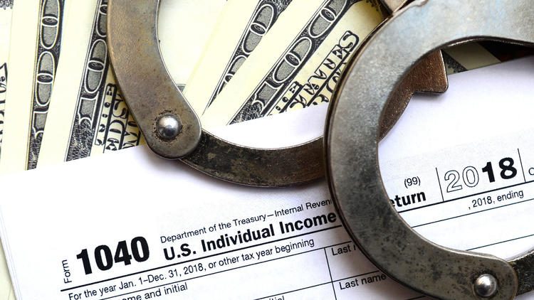 Handcuffs on tax form and dollar bills