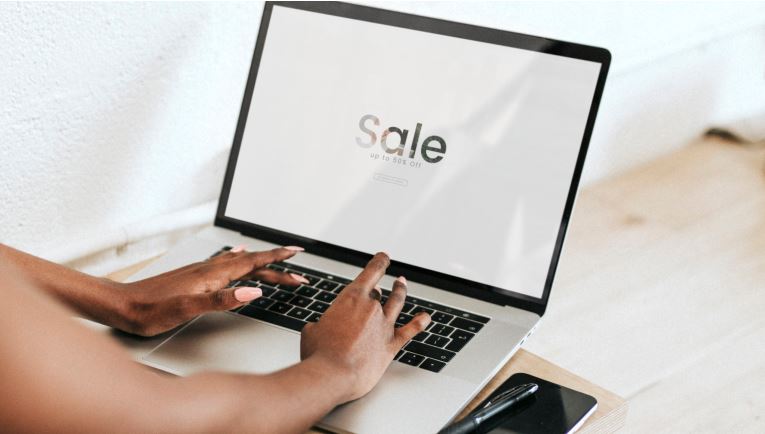 Hands on laptop with sale screen
