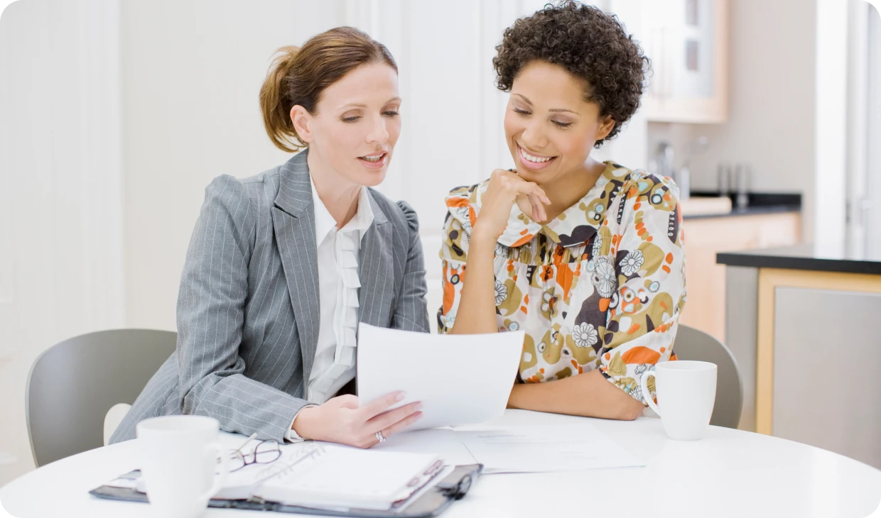 Two women reviewing documents at a table.