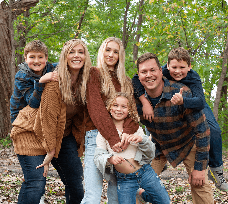 Family posing together in a wooded area.