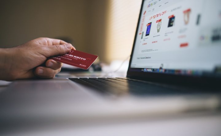 Hand holding credit card near laptop