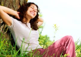 Woman relaxing against a tree outdoors